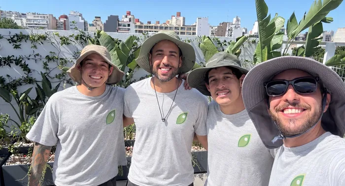 Leandro Vieyra y tres integrantes del equipo de Paisajismo Cuántico, con la remera de la marca, en una terraza